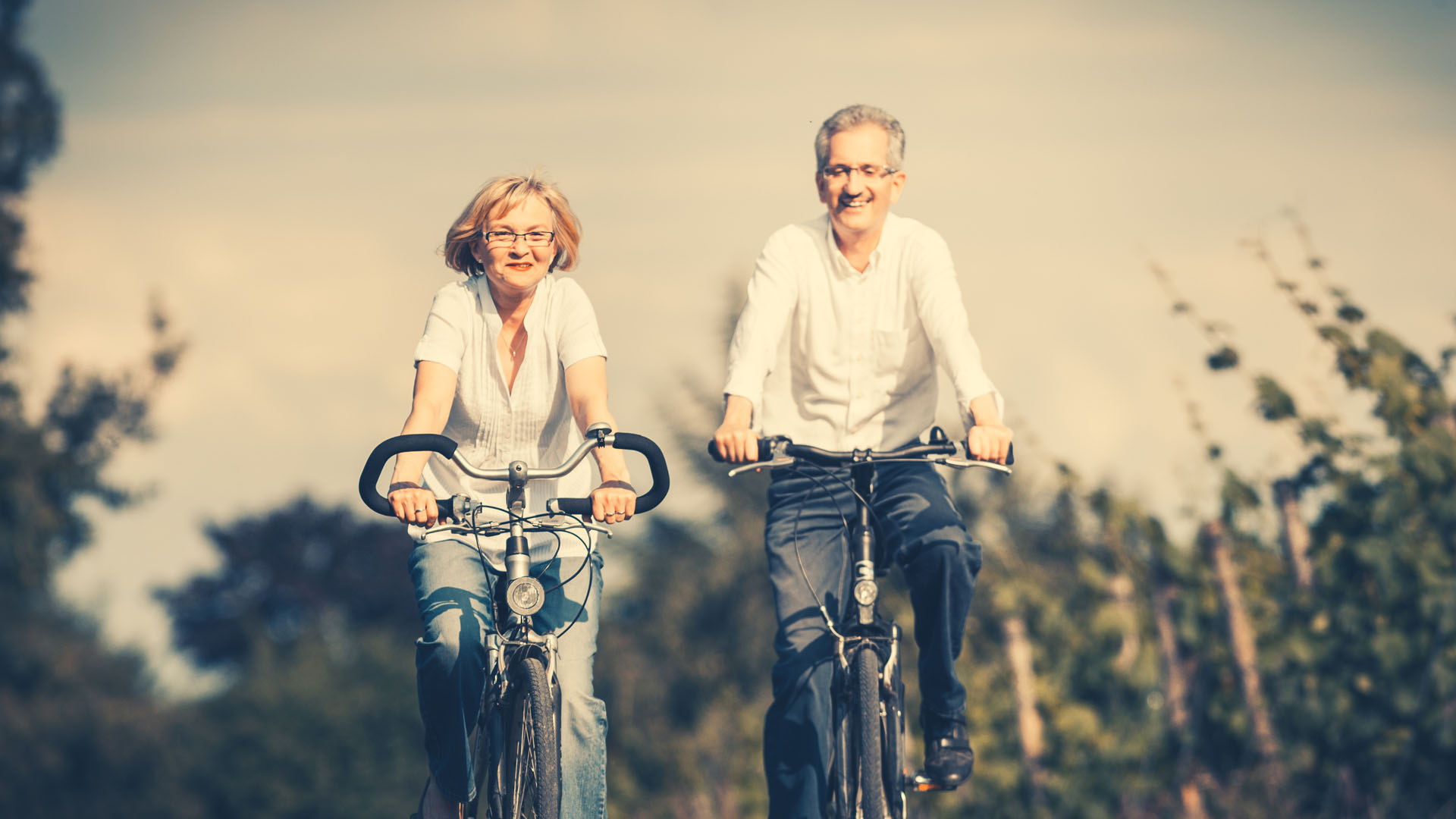 A couple cycling together along a tree-lined path
